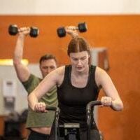 Manic Training High Intensity Workout Woman riding assault bike during strength workout at Manic Training gym